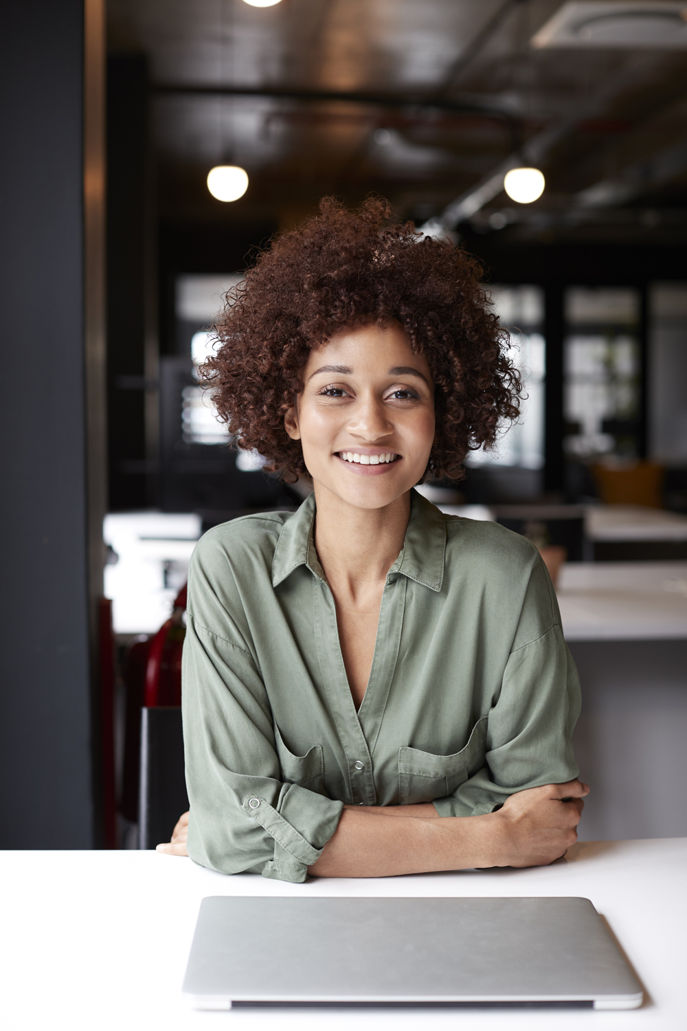 Millennial Black Female Creative Sitting At Desk In An Open Plan